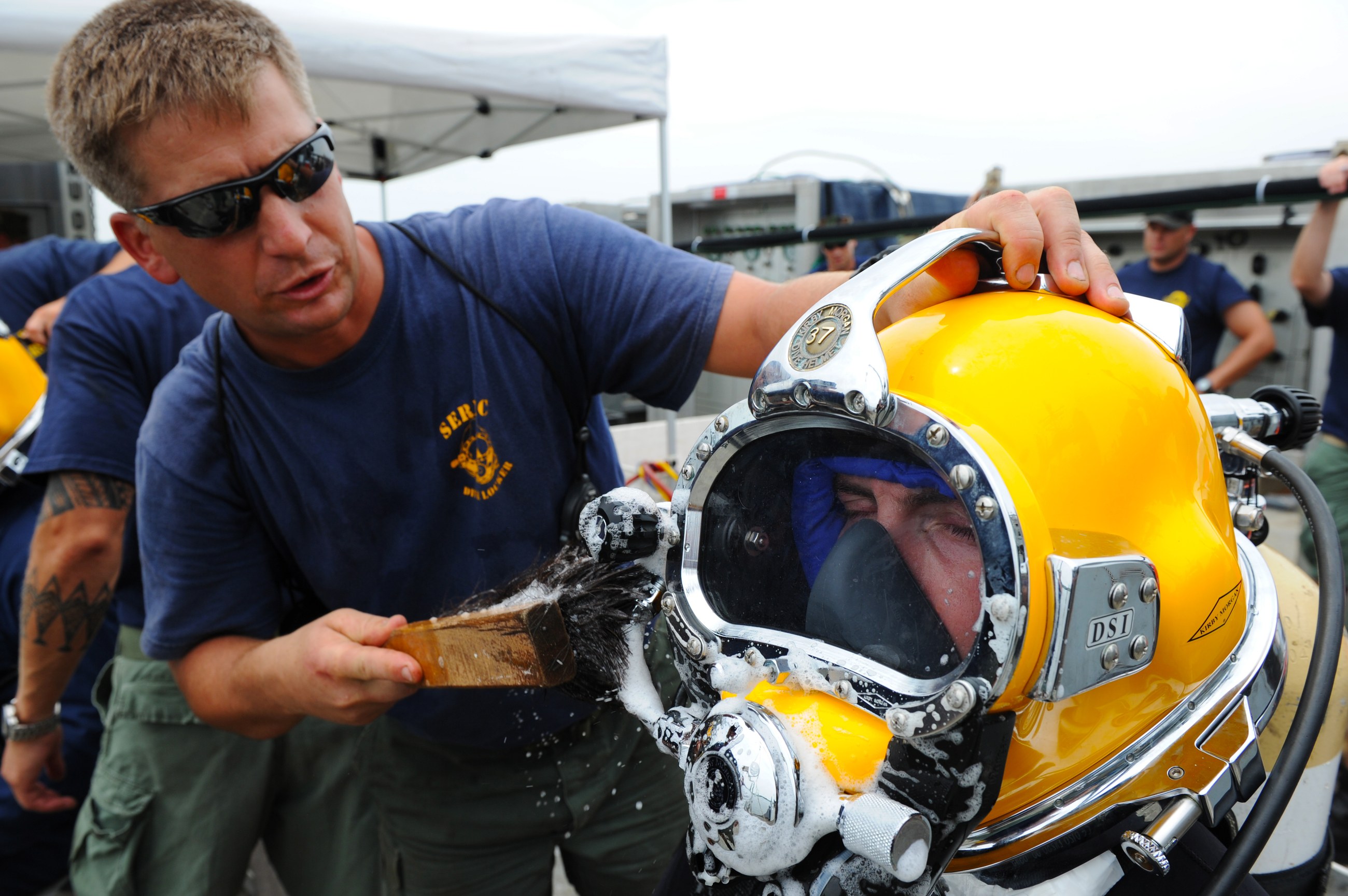 Diving crew checking the air supply connections of a diving helmet before the operation